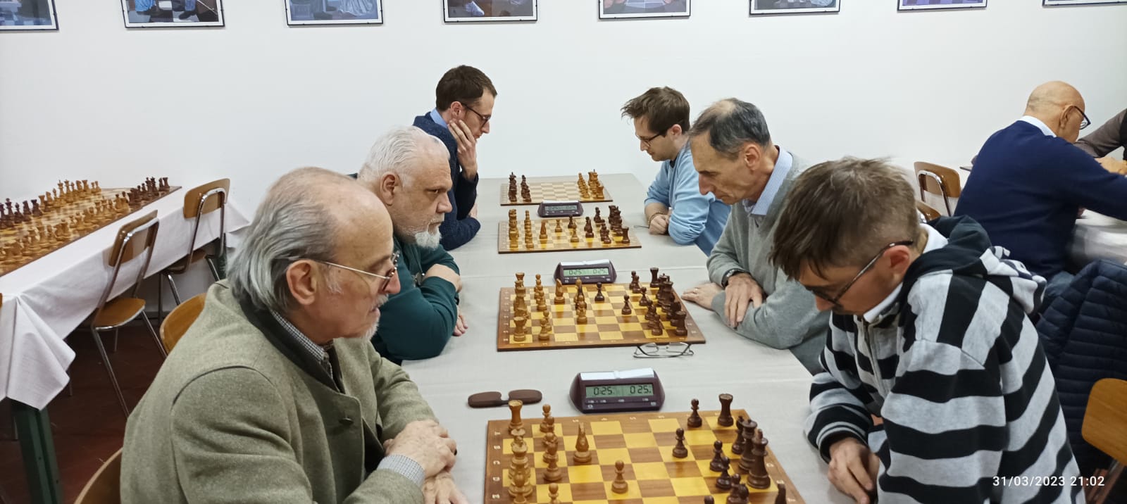 Un gruppo di giocatori di scacchi concentrati mentre partecipano a una partita in un ambiente di competizione.