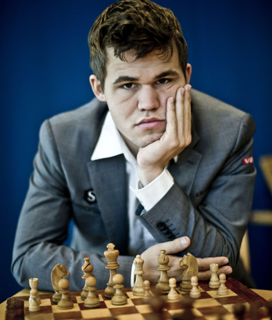 Magnus Carlsen, campione del mondo di scacchi, seduto davanti a una scacchiera con espressione pensierosa.