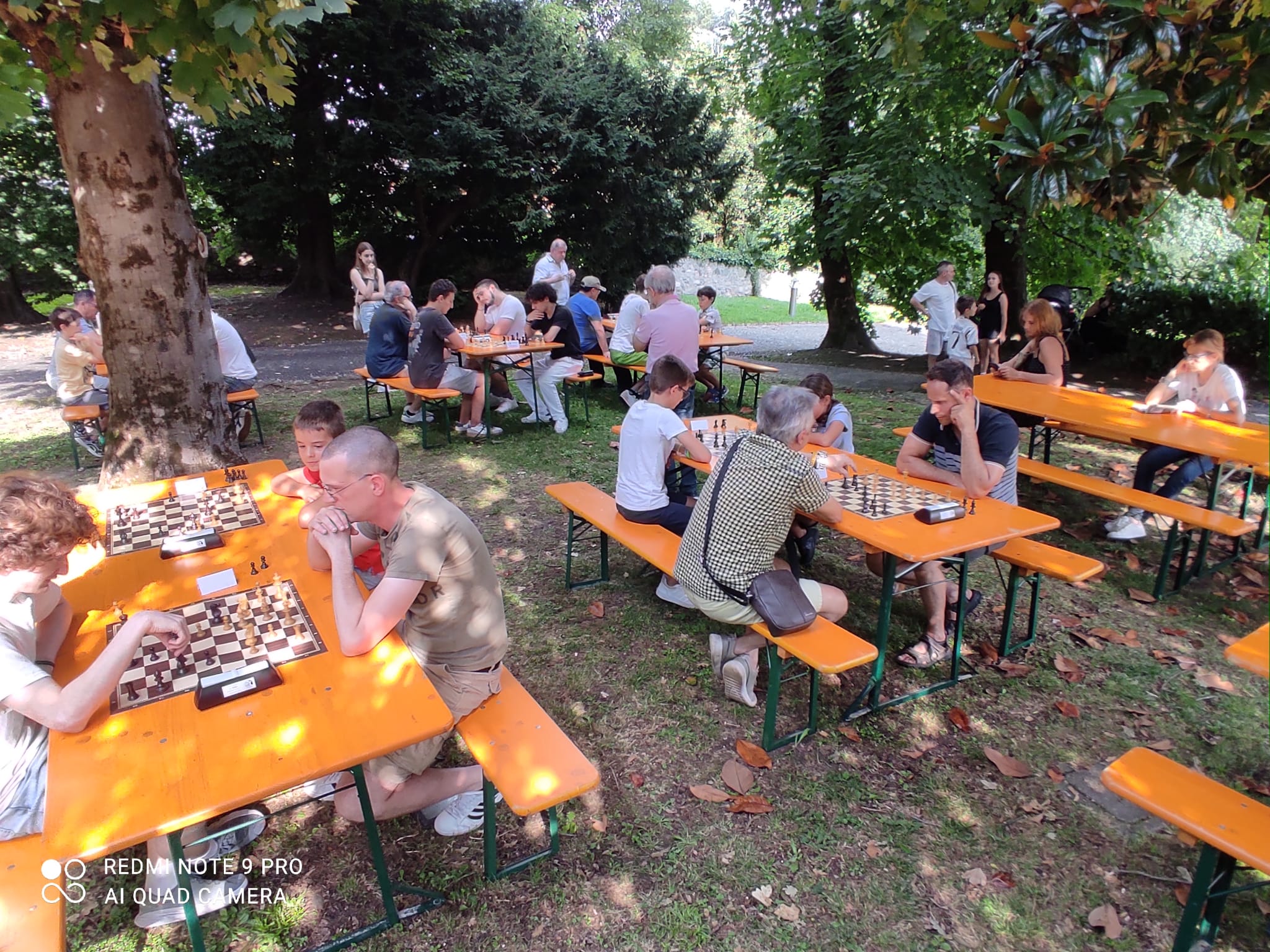 Giocatori di scacchi seduti a tavoli all'aperto durante il torneo nel Parco Comunale di Casnate con Bernate.