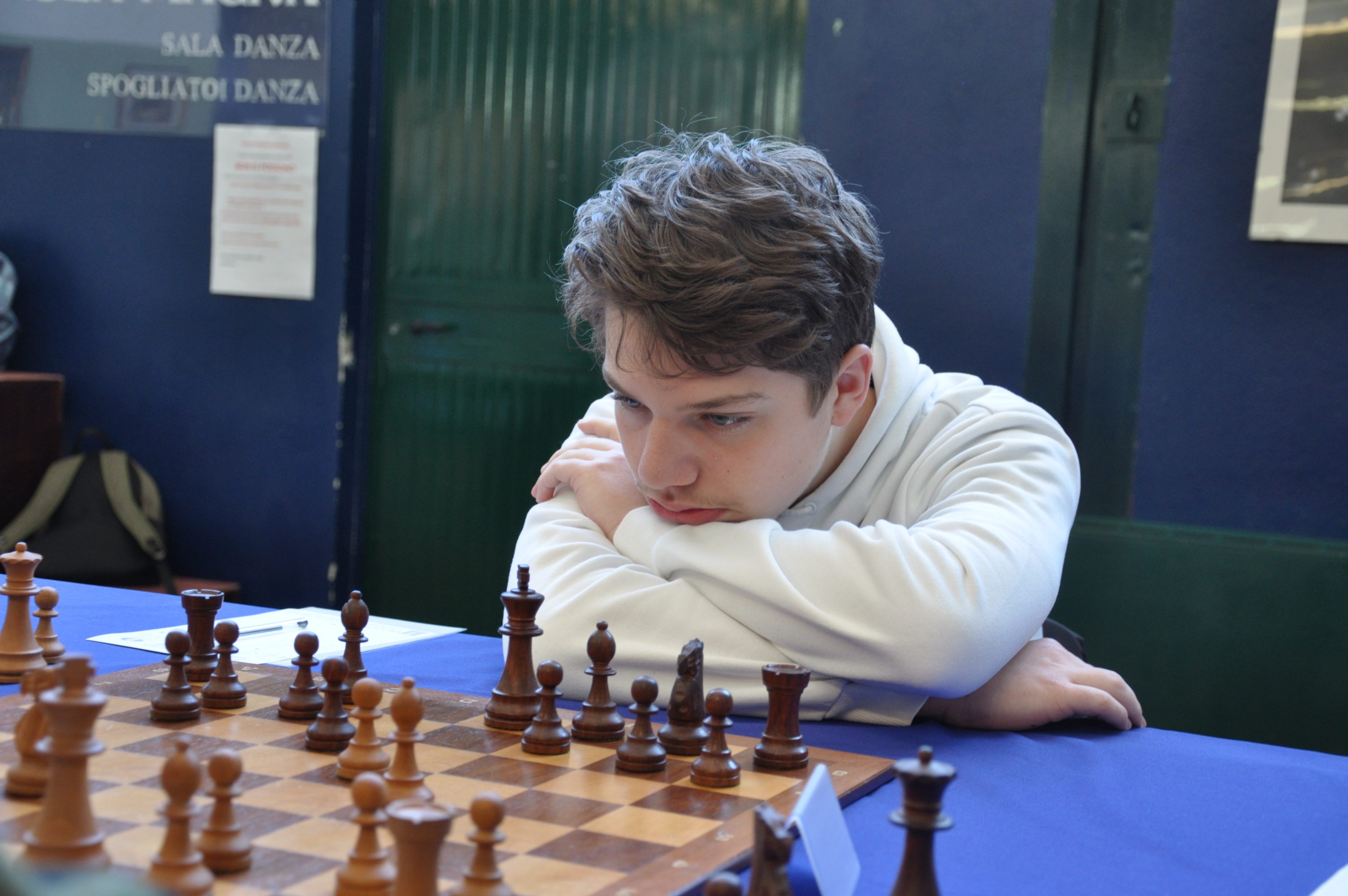 A focused young player analyzing a chessboard during a match.