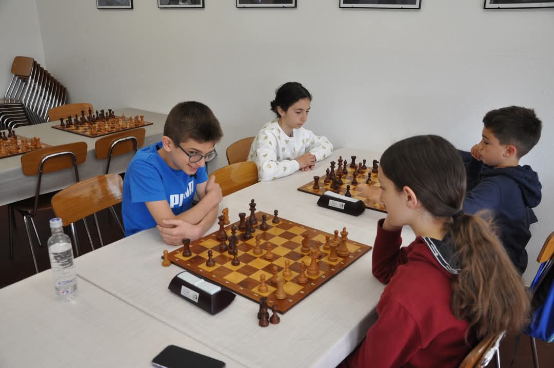 Giovani giocatori di scacchi concentrati durante una partita in un ambiente luminoso.