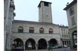 Historic building with stone architecture and a tall clock tower, featuring arched windows and a covered entryway.