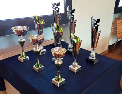 Trofei e coppe esposte su un tavolo coperto da un panno blu, celebrando il torneo di scacchi.