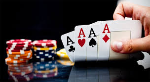 Una mano di poker con tre assi e fiches sul tavolo.