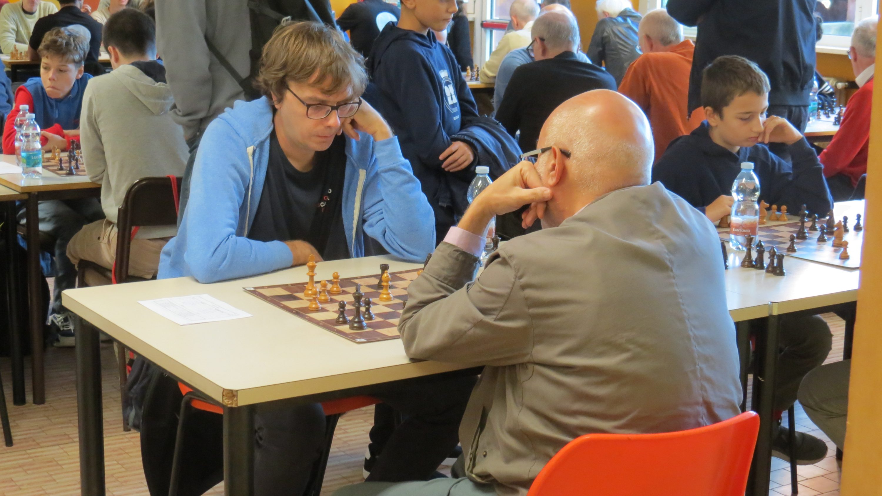 Due giocatori di scacchi concentrati durante una partita in un ambiente affollato.