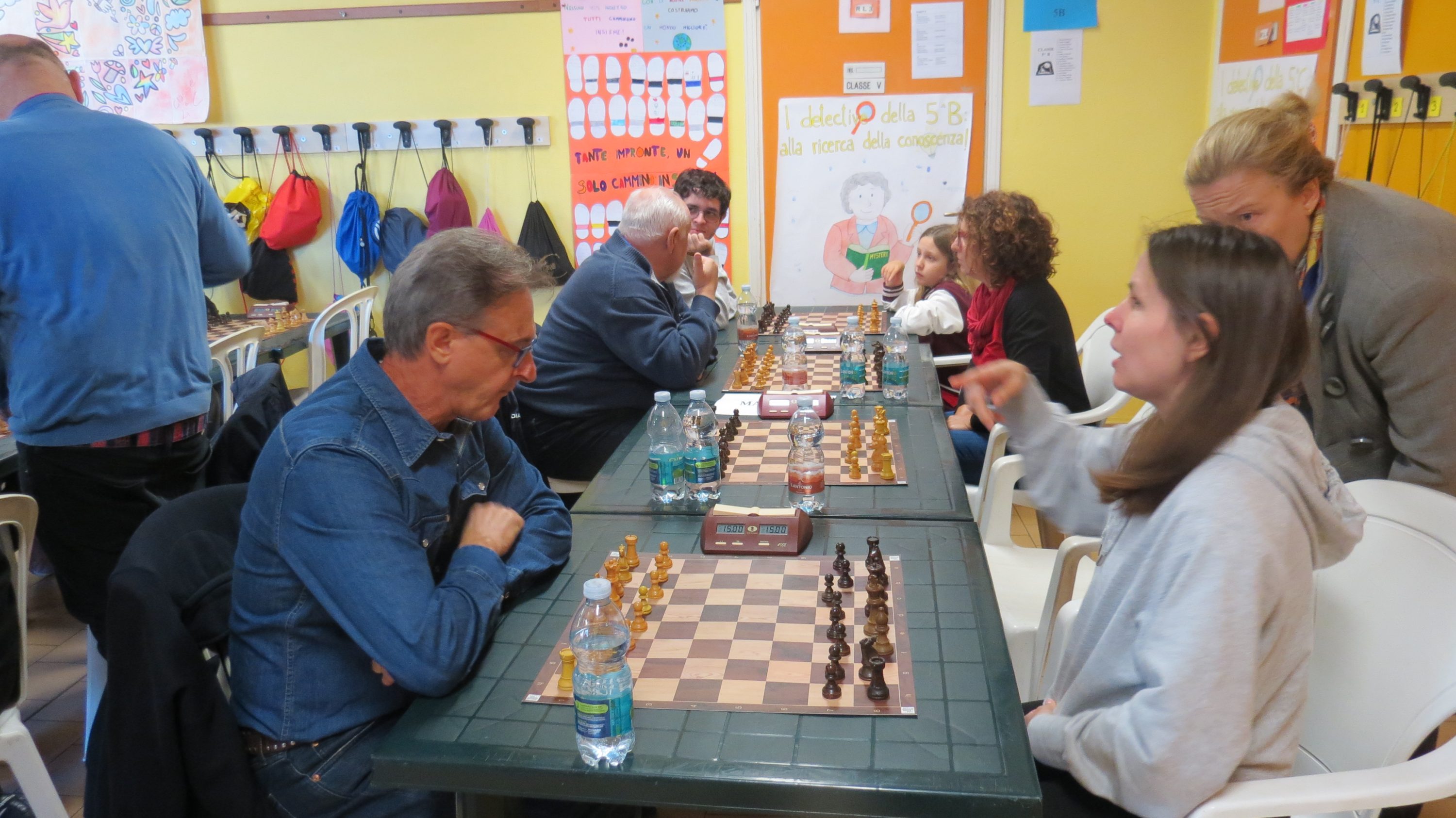 Persone che giocano a scacchi in un ambiente informale, con tavoli e pezzi di scacchi visibili.