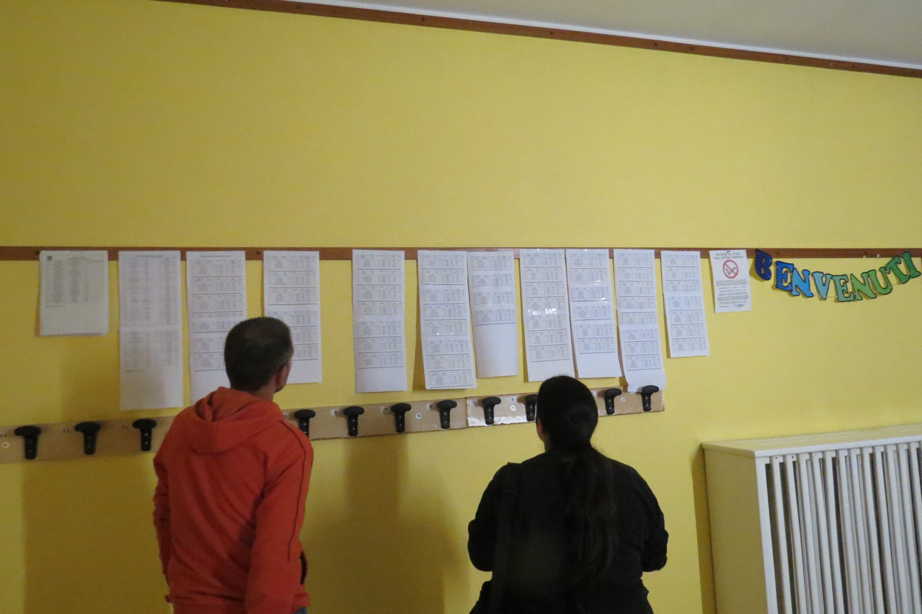 Due persone che leggono documenti appesi a una parete gialla.