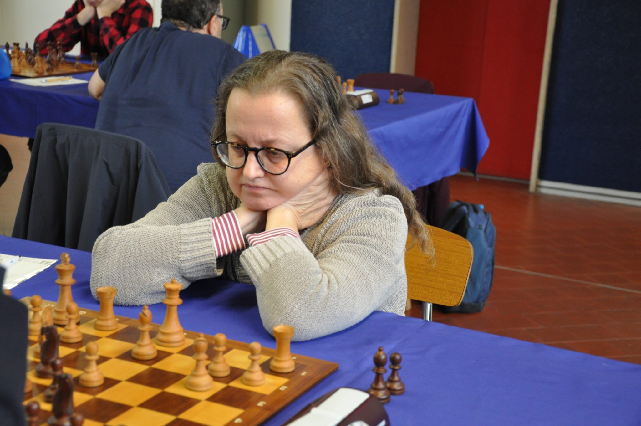 A focused chess player contemplating their next move during a game at a tournament.
