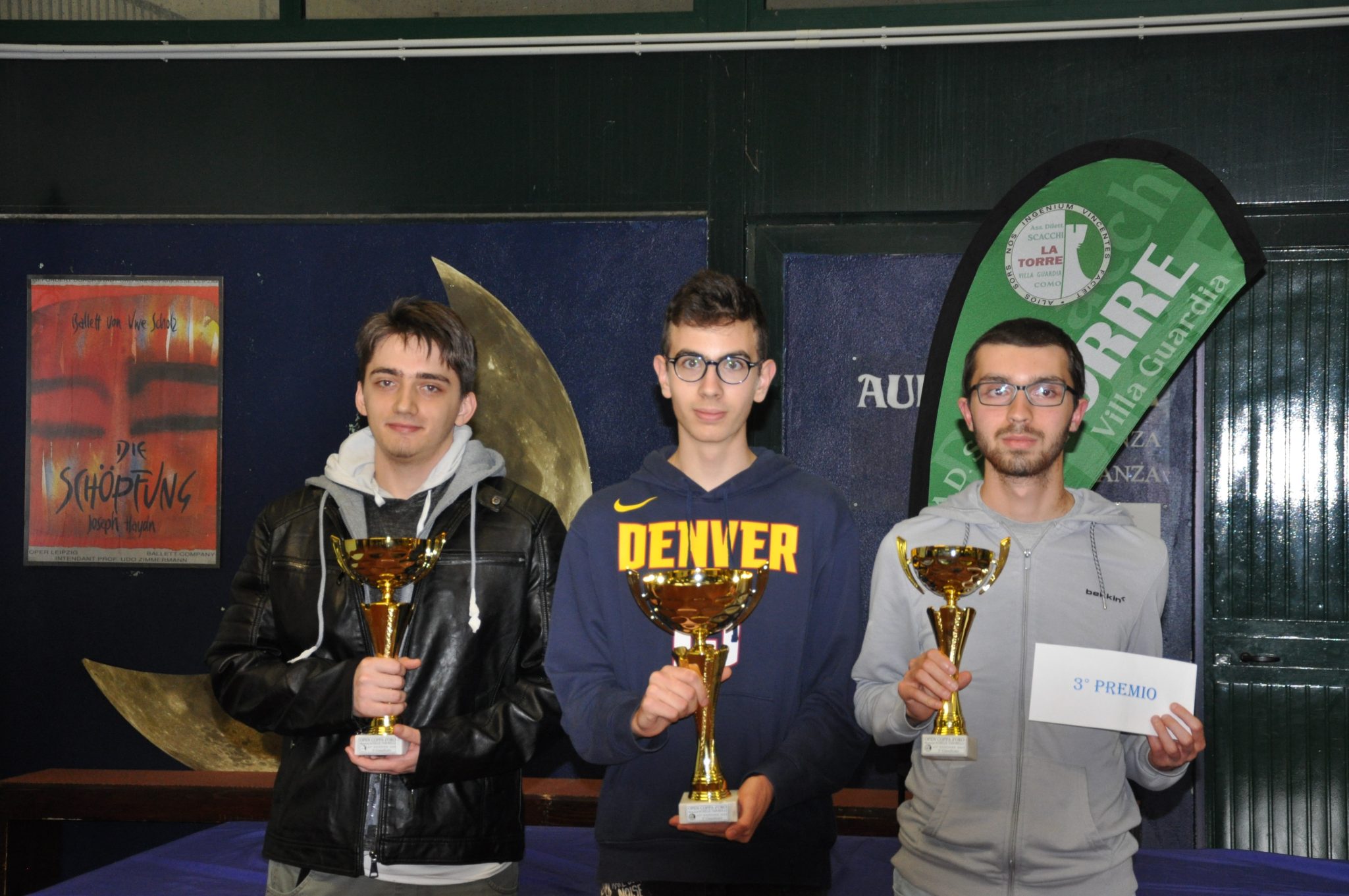 Tre partecipanti al torneo XLI Open Coppadoro tengono trofei di premiazione, sorridendo davanti a uno sfondo decorato.