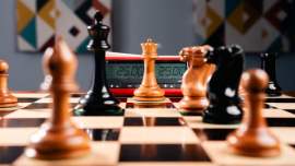 Una scacchiera con pedine nere e bianche in gioco e un cronometro per il tempo di gioco.