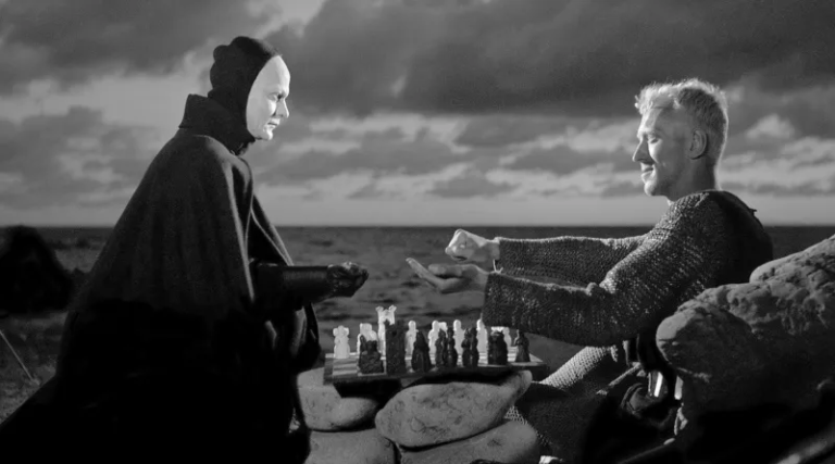 Una scena in bianco e nero che mostra due figure sedute a un tavolo che gioca a scacchi, sullo sfondo di un mare e nuvole.