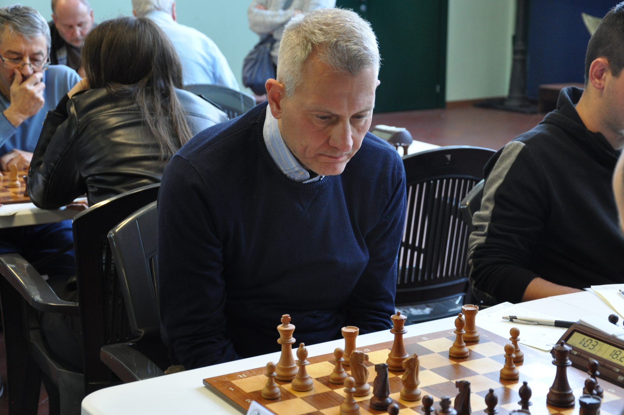 Giocatore di scacchi concentrato mentre gioca una partita, con il tabellone e i pezzi in vista.